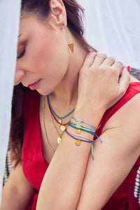 Emily Koliandri is wearing a combo of 4 different necklaces with germstones, silver 925 gold plated chain and silver 925 gold plated charms. And in first plan we see 4 beautiful bracelts in green-blue colors with silver 925 charms with various desings and messages.