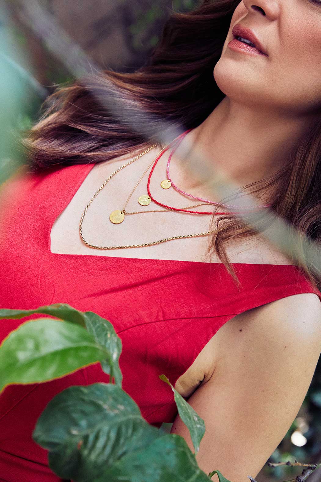 Emily Koliandri is wearing a combo in red tones of 4 necklaces made of japanese miyuki beads, silver 925 gold plated chains, combined with silver 925 gold plated round charms with messages.