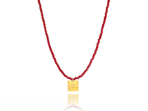 A necklace made of red fire crystal beads and a squared silver 925 charm plated in gold 24K, with a messages like ´´όλα λάθος'' -'It's all wrong! .