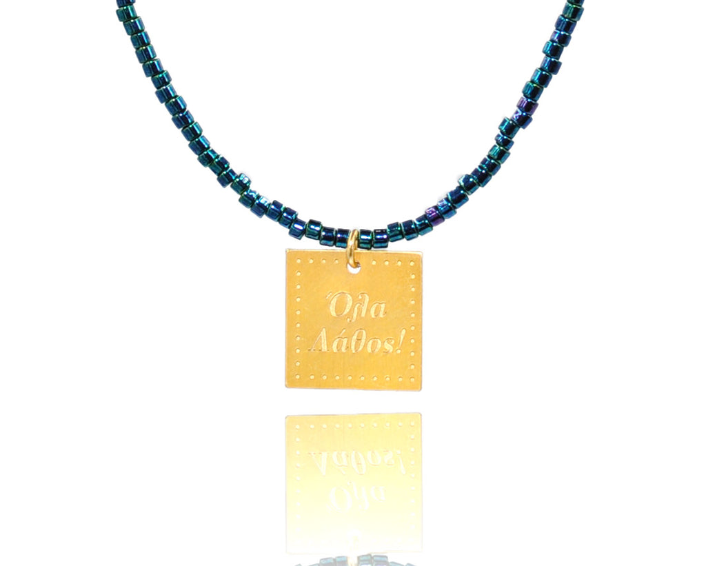 A necklace made of blue japanese miyuki beads and a squared silver 925 charm plated in gold 24K, with a message ´´όλα λάθος'' -'It's all wrong! .