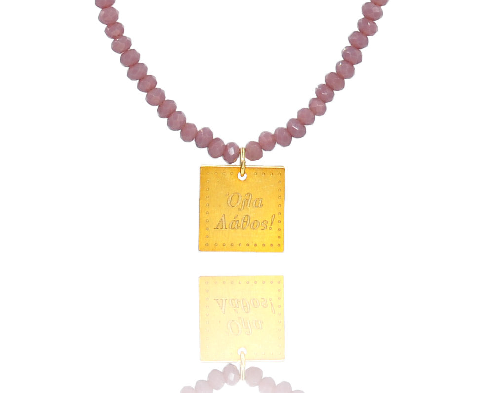A necklace made of lilac crystal beads and a squared silver 925 charm plated in gold 24K, with a message ´´όλα λάθος'' -'It's all wrong! .