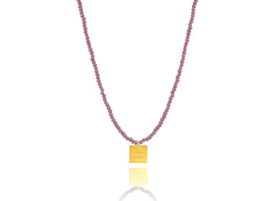 A necklace made of lilac crystal beads and a squared silver 925 charm plated in gold 24K, with a message ´´όλα λάθος'' -'It's all wrong! .